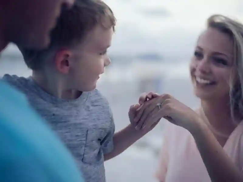 A man is holding a child who is holding his mother's hand, and they are all smiling at each other