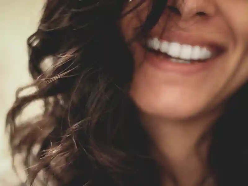 A focused image of a woman with brunette hair smiling with bright white teeth